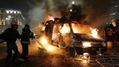 Firefighters and burning vehicle set on fire by protestors