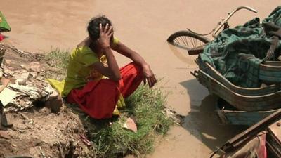 Woman with head in hands, surrounded by flood water