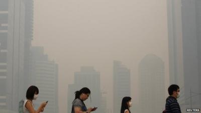 Office workers wearing masks make their way to work in Singapore's central business district on 21 June 2013