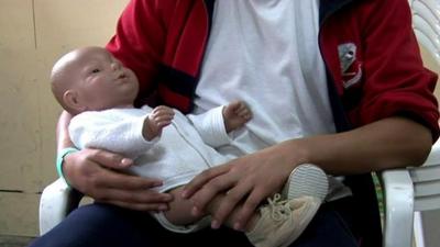 A Colombian teenager holds a robot baby