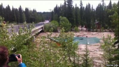 A still from amateur footage shows a roof floating on Bragg Creek, Alberta