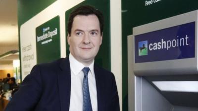 Chancellor George Osborne standing by a cash machine