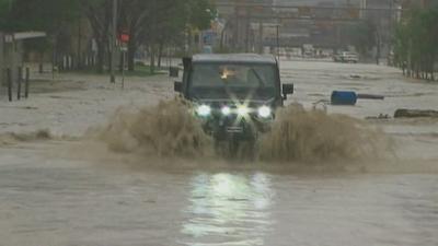 Four-wheel drive vehicle driving through flooded street