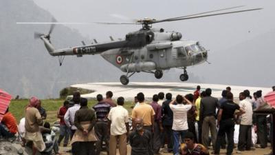 Stranded people rescued by the armed forces from Gaurikund watch a helicopter in Uttarakhand