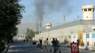 Afghan security forces stand guard as smoke rises from the entrance gate of the presidential palace in Kabul