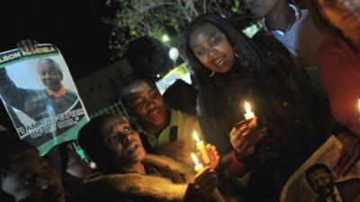 Well-wishers hold candles and photos of Nelson Mandela outside the Mediclinic heart hospital in Pretoria