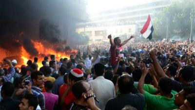 Opponents of Egypt"s Islamist President Mohammed Morsi chant slogans as fire rages at the Muslim Brotherhood headquarters in Alexandria