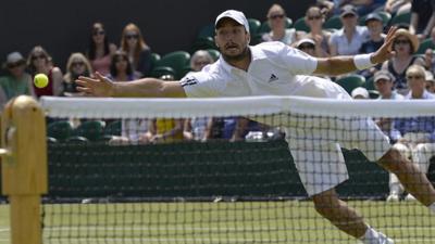 Viktor Troicki attempts to hit the ball with his hand after dropping his racket