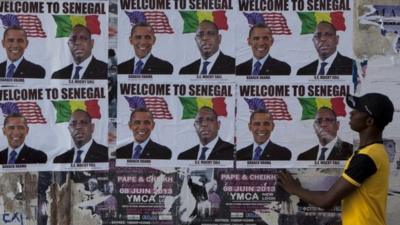 A passerby stops to look at signs showing US President Barack Obama alongside Senegalese President Macky Sall and reading "Welcome to Senegal" in Dakar, Senegal, Wednesday 26 June 2013