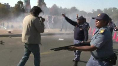 A police officer holding a gun at an anti-US demonstration in Soweto