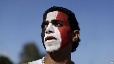 An opponent of Egypt's Islamist President Mohammed Morsi with his face painted with the colours of the Egyptian flag stands outside the presidential palace in Cairo.