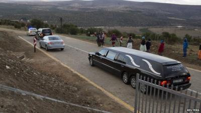 A convoy of police and funeral vehicles approaches the homestead of Mandla Mandela