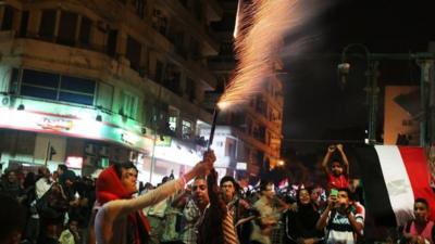 People hold fireworks in Tahrir Square on Thursday