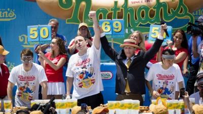 Joey Chestnut, (c), wins the hot dog eating contest