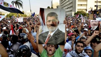 Egyptian supporters of the Muslim Brotherhood hold pictures of deposed president Mohamed Morsi