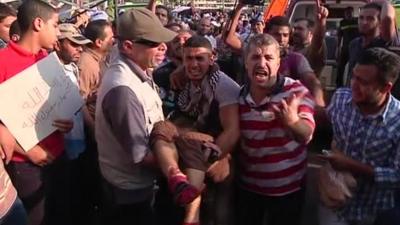 An injured man being carried through the crowd