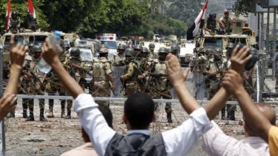 Supporters of deposed President Morsi shout slogans in front of army soldiers