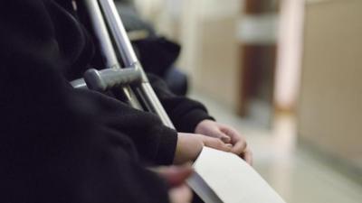 Unidentified patient with crutches holds paperwork