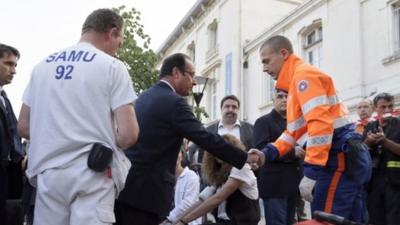 French President Francois Hollande (C) shakes hands with a rescue worker