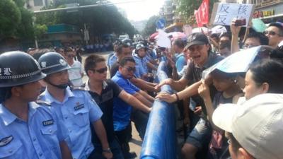 Police stand across demonstrators during a protest against plans for a uranium processing plant in Jiangmen, Guangdong province