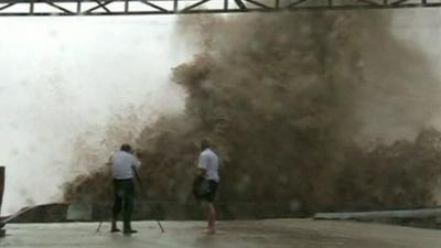 Two people photograph a wave