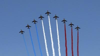 Nine jets from the French Air Force Patrouille de France releasing trails of red, white and blue smoke