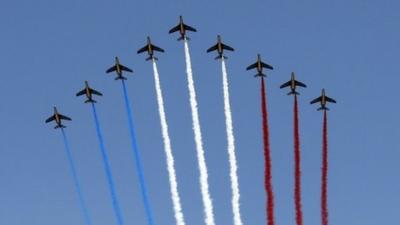 Nine jets from the French Air Force Patrouille de France releasing trails of red, white and blue smoke