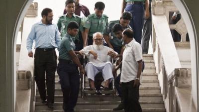 Ghulam Azam is escorted by security personnel and lawyers as he emerges from the Bangladesh International Crimes Tribunal in Dhaka on January 11, 2012