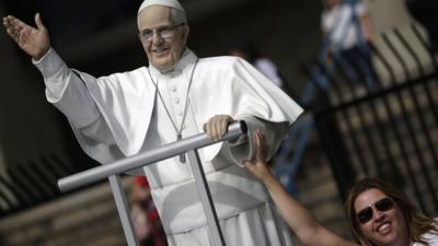 A woman poses with a statue of the Pope Francis in Rio de Janeiro