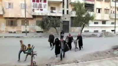 Residents run across a street in Aleppo