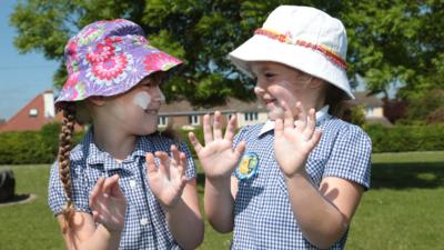 Children with sun cream and hats on.