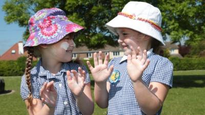 Children with sun cream and hats on.