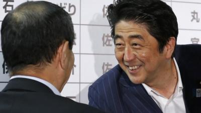 Japanese Prime Minister Shinzo Abe, right, exchanges smiles with Secretary General Shigeru Ishiba of the ruling Liberal Democratic Party during ballot counting