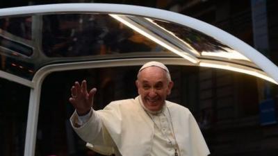 Pope Francis waves at the faithful from the Popemobile