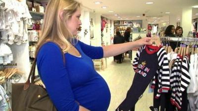 Woman looking at royal-themed baby clothes