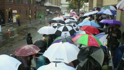 The world's media with umbrellas outside hospital