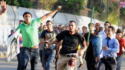 A supporter of ousted President Mohammed Morsi (centre) runs from pro-government and army supporters