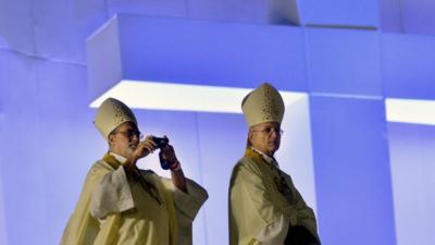 A bishop takes snapshots before the start of the World Youth Day (WYD) opening mass, at Copacabana beach in Rio de Janeiro, Brazil