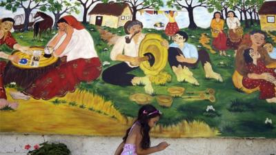 A girl walks by a Roma mural in Hungary