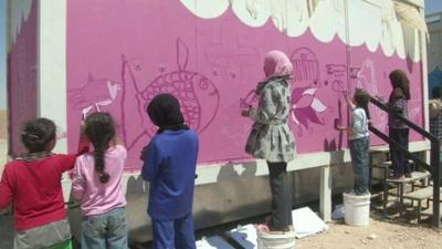 Syrian refugee children paint a wall