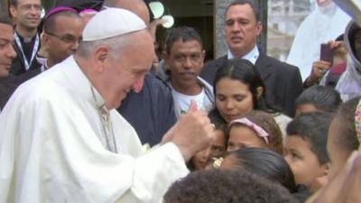 Pope Francis smiles and gives a thumbs-up to children he has just blessed