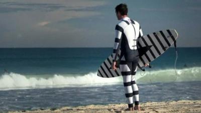 A surfer wearing a black and white striped wetsuit