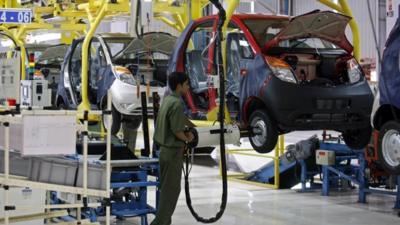 An employee works on a Tata Nano car