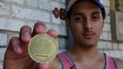 Man holds a GPS tracking coin