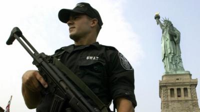 Police officer in SWAT uniform in front of Statue of Liberty