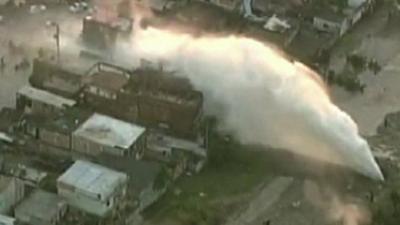 Burst water pipe pouring water onto nearby buildings