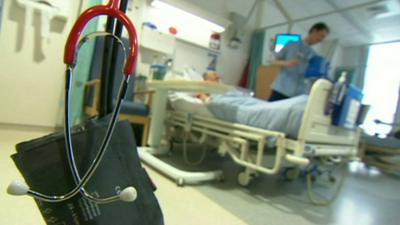 Stethoscope and blood pressure cuff in front of nurse checking on patient