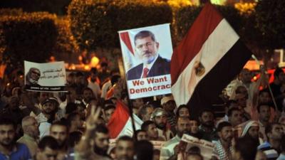 Pro-Morsi supporters holding pictures waving flags