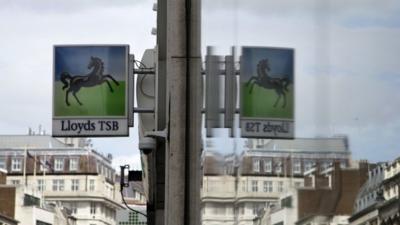 Lloyds bank sign reflected in window outside branch