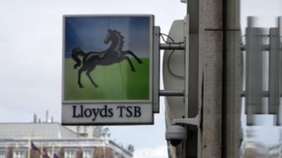 Lloyds bank sign reflected in window outside branch